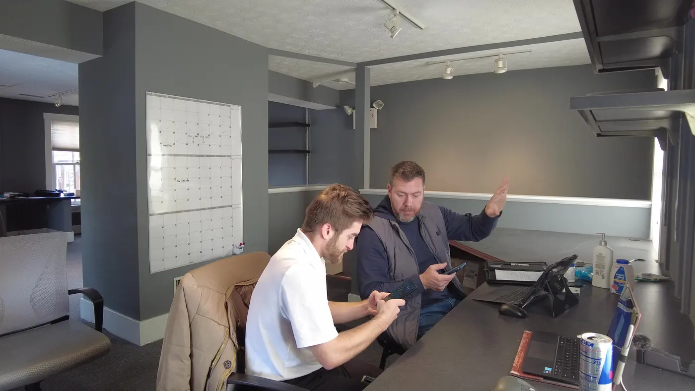 Noah coaching a roofing rep at his desk