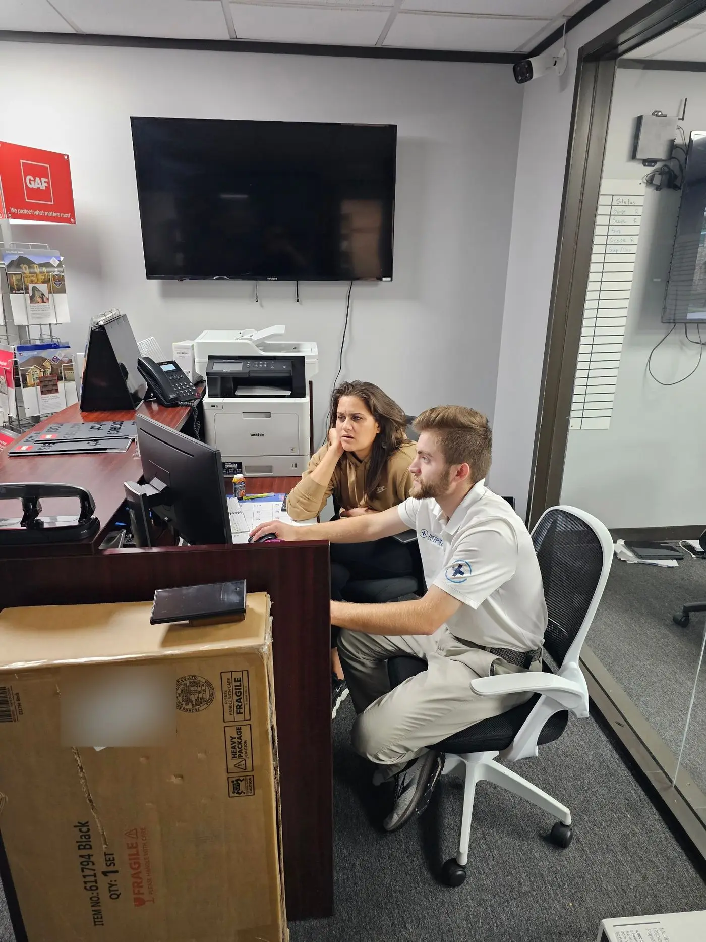 Noah working at an office computer with a team member