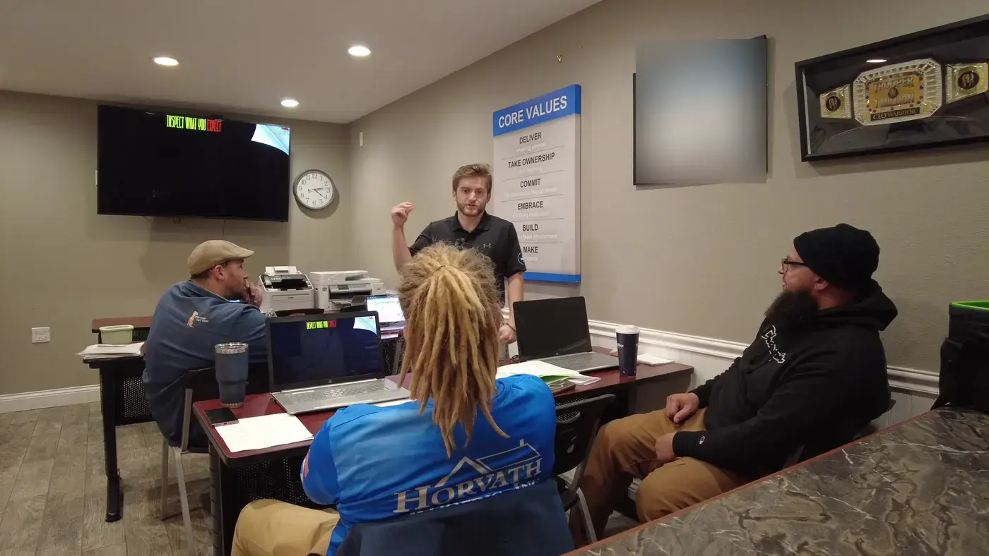 Noah teaching the Horvath Roofing team beside their core values board