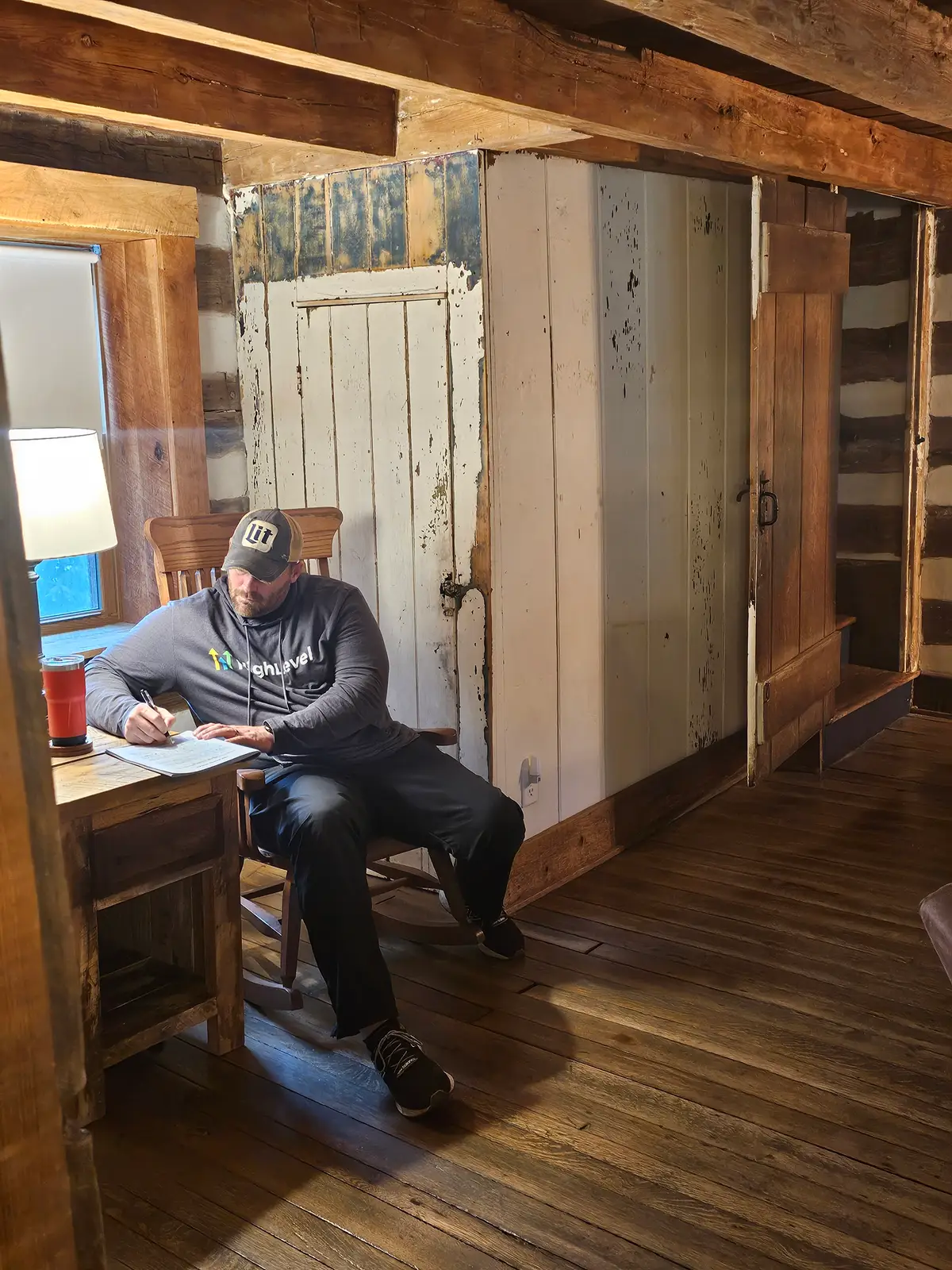 A sales rep writing in his workbook at a desk by the window